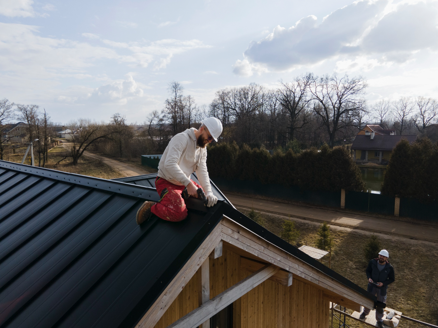 Roofer installing a dark metal roof on a Vancouver Island home